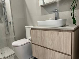 a bathroom with a sink and a toilet and a shower at Lovely City 1BR Apt Free Parking & Facing Mall in Canberra