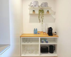 a white shelf with wine glasses on it at Lovely City 1BR Apt Free Parking & Facing Mall in Canberra