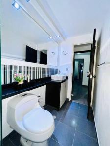 a bathroom with a white toilet and a sink at Hermoso y Familiar Apartamento Cedritos in Bogotá