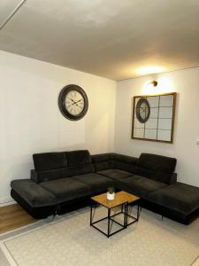 uma sala de estar com um sofá preto e um relógio em Paris- Stade de France -CDG-Disney em Saint-Denis