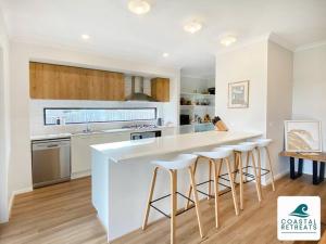 a kitchen with a white counter and bar stools at Scotty’s Place – Luxury Retreat in Inverloch