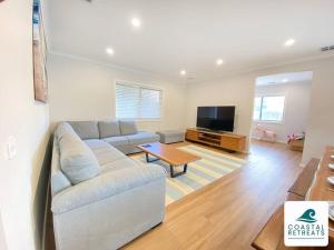 a living room with a couch and a tv at Scotty’s Place – Luxury Retreat in Inverloch