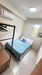 a small bedroom with a bed and a window at Jardim das Palmeiras II Home Resort in Ubatuba
