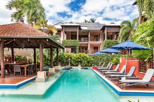 a resort swimming pool with chairs and umbrellas at Hibiscus Resort & Spa with Onsite Reception & Check In in Port Douglas