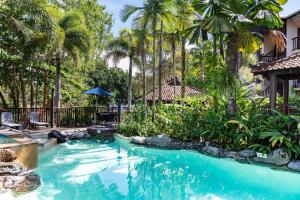 a swimming pool in a resort with palm trees at Hibiscus Resort & Spa with Onsite Reception & Check In in Port Douglas