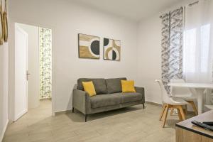 een woonkamer met een grijze bank en gele kussens bij Alcam Baro 22 in Barcelona