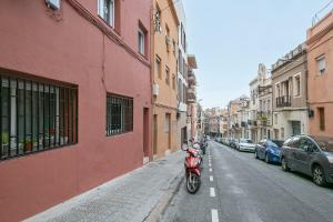 een rode motorfiets geparkeerd aan de kant van een straat bij Alcam Baro 22 in Barcelona