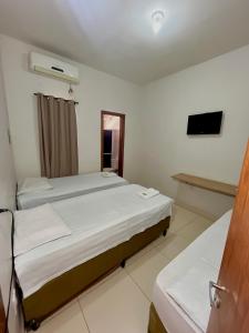 a hotel room with two beds and a television at Kitnet Realeza in Várzea Grande