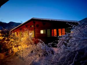 una cabaña cubierta de nieve por la noche con luces en Gstaad Chalet en Gstaad