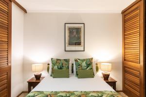 um quarto com uma cama branca e 2 candeeiros em Hibiscus Resort & Spa with Onsite Reception & Check In em Port Douglas