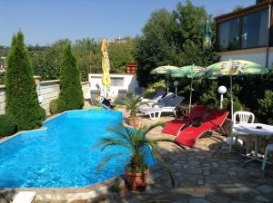 a swimming pool with chairs and umbrellas on a patio at Villa Olymp in Golden Sands