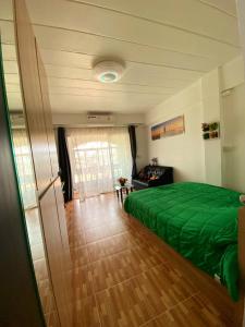 芭達雅中心的住宿－Nirun Grand Ville C4，一间卧室设有绿色的床,铺有木地板