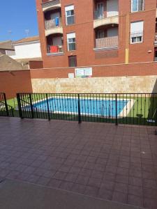 a fence in front of a building with a swimming pool at Apartamento Haire in San Pedro del Pinatar