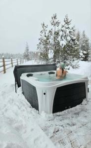 a person sitting in a hot tub in the snow at Woodhouse Cottages And Ranch in Prince George