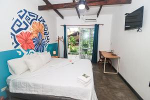 - une chambre avec un lit blanc orné d'une peinture murale dans l'établissement HOTEL CAREY, à Pedasí Town