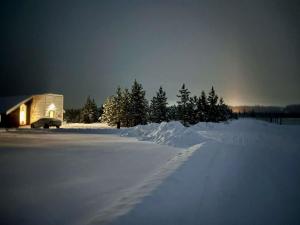 a snow covered field with a barn and trees at Woodhouse Cottages And Ranch in Prince George