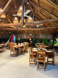 un restaurante con mesas de madera, sillas y lámparas de araña en Ecohabs Bamboo Parque Tayrona - Dentro del PNN Tayrona en El Zaino