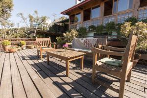 a patio with a wooden table and chairs on a deck at Pousada Benevento in Campos do Jordão