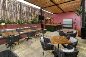 オアハカにあるCity Centro by Marriott Oaxacaの木製のテーブルと椅子、バーのあるレストラン