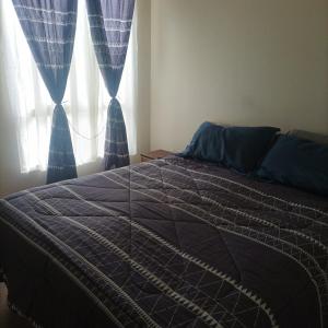 1 cama en un dormitorio con cortinas azules y ventana en Amplio y comodo departamento, en La Serena