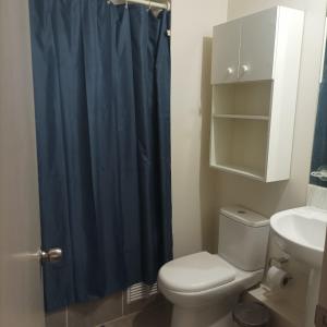 a bathroom with a toilet and a blue shower curtain at Amplio y comodo departamento in La Serena