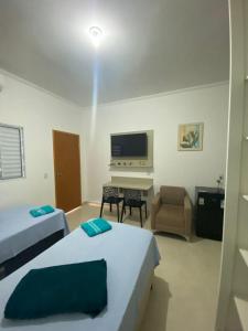 1 dormitorio con 2 camas, escritorio y TV en Vaz Lobo Kitnets, en Mococa