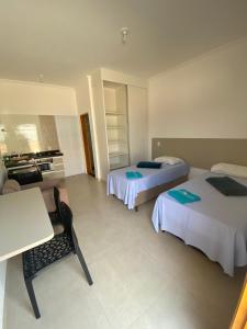a hotel room with two beds and a table at Vaz Lobo Kitnets in Mococa +27 photos