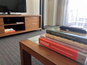 a stack of books sitting on a table next to a tv at 109 Simply Devine Hay St 2x2apt Poolgym in Perth