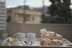 - un plateau avec des tasses de café et une boîte de pâtisseries dans l'établissement REDAMARE SUITE, à Lago Patria