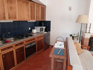 a kitchen with wooden cabinets and a couch in a room at Casa das Oliveiras - Manteigas in Manteigas