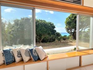 een stoel bij het raam met kussens en uitzicht op de oceaan bij Ie shima-MONKEY - Vacation STAY 48431v in Ie