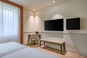 Schlafzimmer mit einem Bett, einem Schreibtisch und einem TV in der Unterkunft AC Hotel Los Vascos by Marriott in Madrid