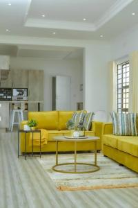 ein Wohnzimmer mit einem gelben Sofa und einem Tisch in der Unterkunft Crystal Apartments Area 43 in Lilongwe