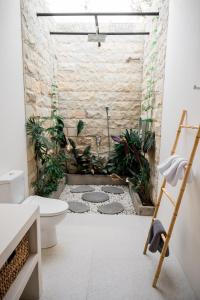 a bathroom with a toilet and plants on the floor at Shanti Boutique Retreat in Tanah Lot