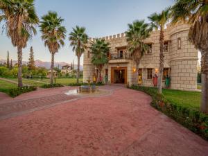 un bâtiment avec des palmiers en face de celui-ci dans l'établissement Castle d'Atlas Riad & Spa, à Marrakech