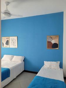 two beds in a room with a blue wall at Casas Rio de Contas in Rio de Contas