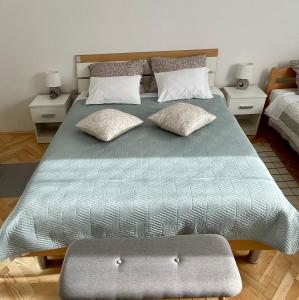 ein großes Bett mit einer grünen Bettdecke und Kissen in der Unterkunft Apartman Noel Knin in Knin