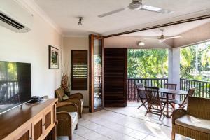a living room with a balcony with a table and chairs at Hibiscus Resort & Spa with Onsite Reception & Check In in Port Douglas
