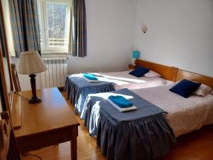 two beds in a room with a table and a lamp at Casa das Oliveiras - Manteigas in Manteigas