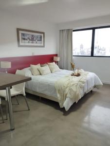 a white bedroom with a large bed and a table at HERMOSO MONOAMBIENTE A POCAS CUADRAS DEL RIO! in Rosario