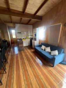 uma sala de estar com um sofá azul e uma cozinha em Cabaña Lago Ranco, puerto nuevo em Puerto Nuevo