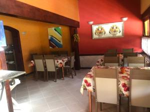 um restaurante com mesas e cadeiras e uma parede vermelha em VILLA MIA DUO em Itaipava