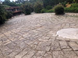 un patio de piedra con una casa al fondo en VILLA MIA DUO en Itaipava