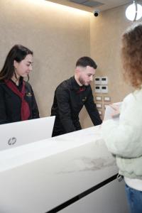 Ein Mann und eine Frau stehen vor einer Theke in der Unterkunft Troci Hotel in Tirana