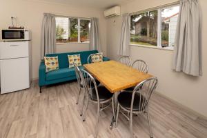 a living room with a blue couch and a table and chairs at Ohakune TOP 10 Holiday Park in Ohakune