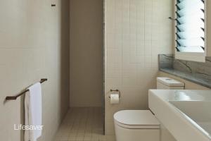 a white bathroom with a toilet and a sink at Bluewater on the Beach in Byron Bay