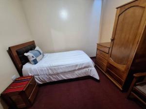 ein kleines Schlafzimmer mit einem Bett und einer Holzkommode in der Unterkunft Cozy private home overlooking the Vilcanota river in Pisac