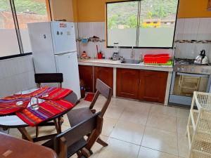 eine Küche mit einem Tisch und einem weißen Kühlschrank in der Unterkunft Cozy private home overlooking the Vilcanota river in Pisac