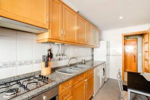 eine Küche mit Holzschränken und einer Spüle in der Unterkunft Apartamento em Lisboa, perto de Sintra in Fontainhas + 15 Fotos