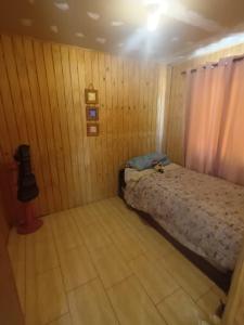 una piccola camera con un letto su una parete in legno di Cabañas Sofi a Quillón